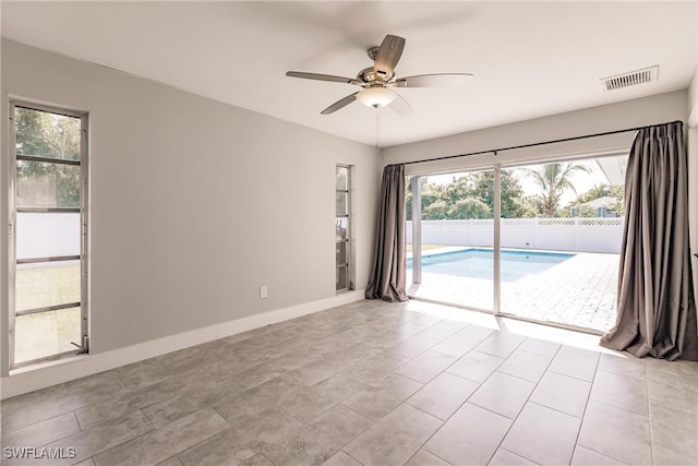 empty room featuring plenty of natural light, visible vents, ceiling fan, and baseboards