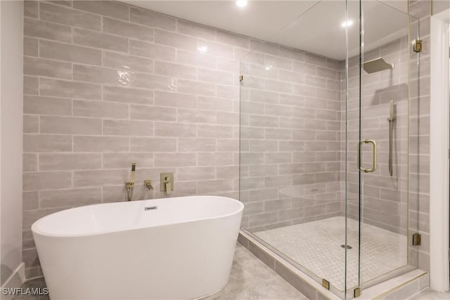 full bathroom with a stall shower, a soaking tub, tile patterned flooring, and tile walls