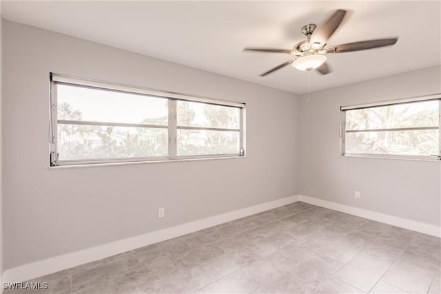 empty room with a ceiling fan, baseboards, and a wealth of natural light