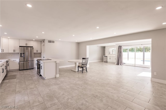 kitchen featuring visible vents, white cabinets, open floor plan, stainless steel appliances, and light countertops