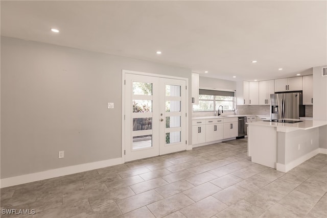 kitchen featuring french doors, stainless steel appliances, light countertops, white cabinets, and a sink