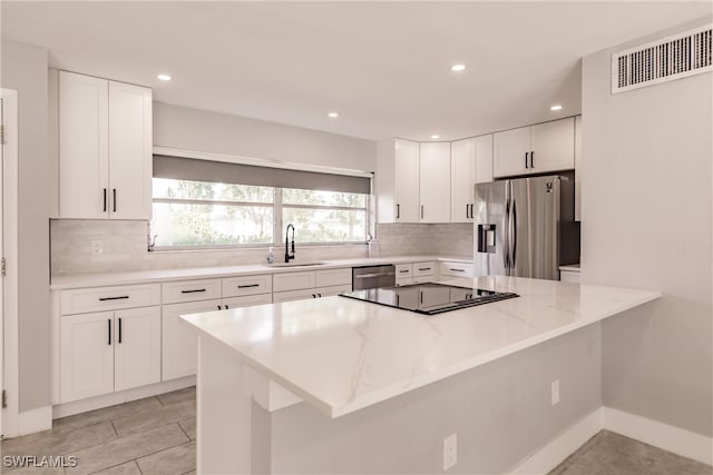 kitchen featuring stainless steel appliances, visible vents, decorative backsplash, white cabinets, and a sink