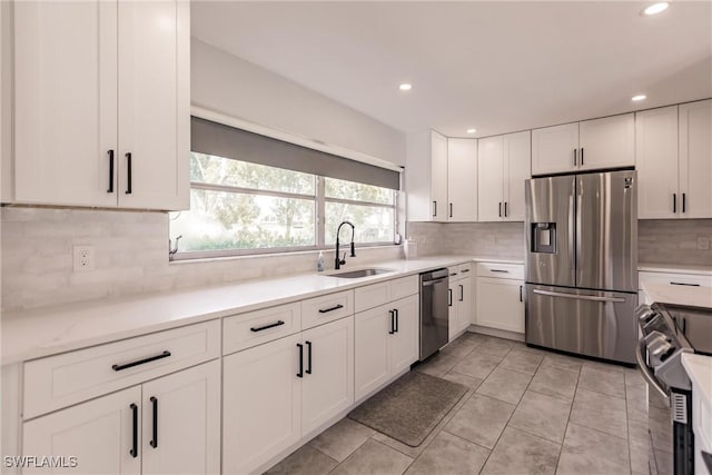 kitchen featuring tasteful backsplash, appliances with stainless steel finishes, a sink, and white cabinets