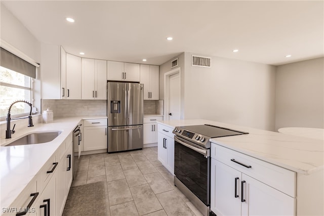 kitchen featuring a sink, visible vents, white cabinets, appliances with stainless steel finishes, and decorative backsplash