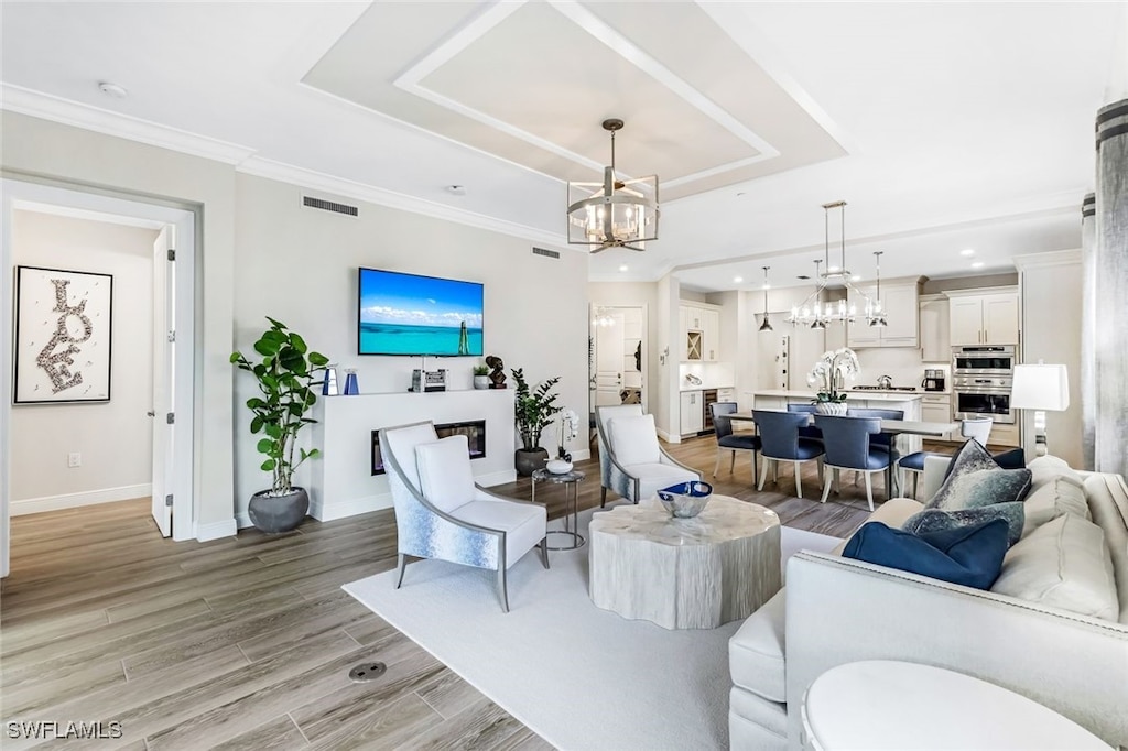 living room featuring light hardwood / wood-style flooring, an inviting chandelier, and ornamental molding