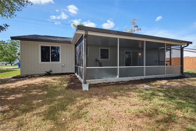 back of property with a yard and a sunroom