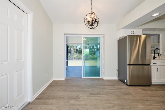 unfurnished dining area with light hardwood / wood-style floors, an inviting chandelier, and sink