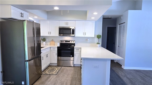 kitchen featuring kitchen peninsula, white cabinetry, stainless steel appliances, and dark wood-type flooring