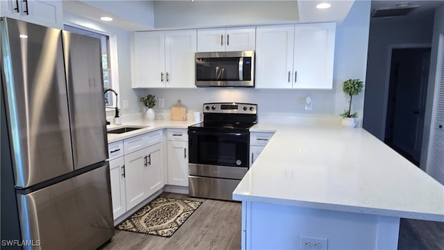 kitchen with white cabinetry, kitchen peninsula, sink, and appliances with stainless steel finishes