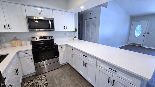 kitchen featuring white cabinetry, kitchen peninsula, stainless steel appliances, and dark wood-type flooring