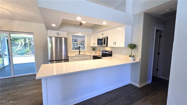 kitchen with white cabinets, appliances with stainless steel finishes, kitchen peninsula, and sink