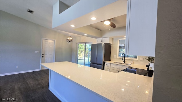 kitchen with kitchen peninsula, stainless steel fridge, sink, dark hardwood / wood-style floors, and white cabinetry