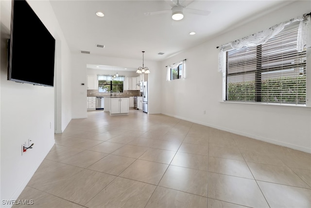 unfurnished living room with ceiling fan with notable chandelier and light tile patterned floors