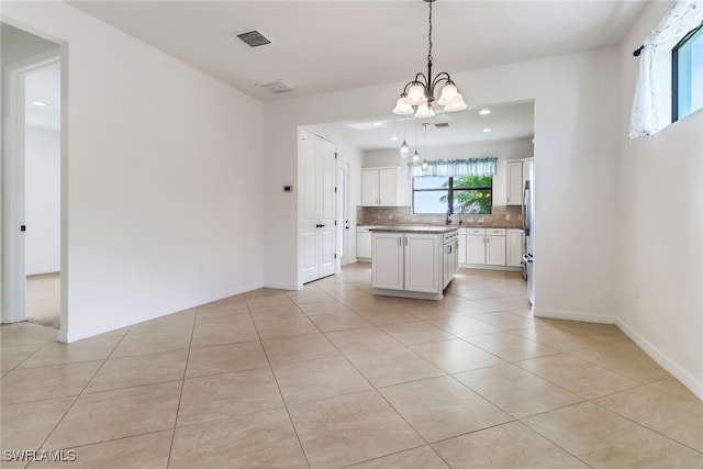 kitchen with backsplash, a center island, decorative light fixtures, white cabinets, and a notable chandelier