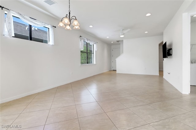 spare room with washer / clothes dryer, ceiling fan with notable chandelier, and light tile patterned floors