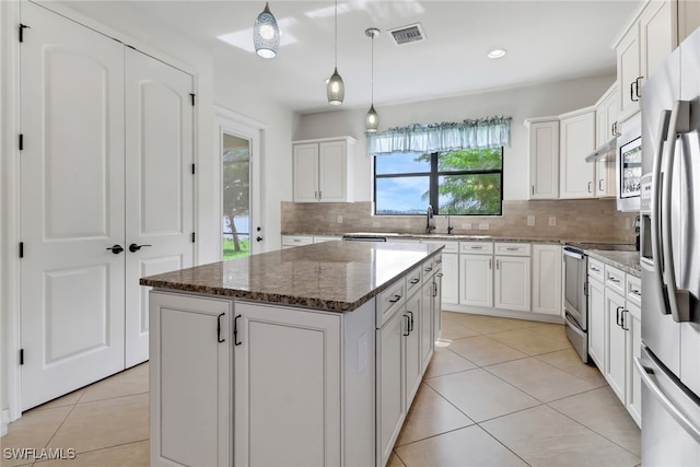 kitchen featuring tasteful backsplash, a center island, dark stone counters, and white cabinets