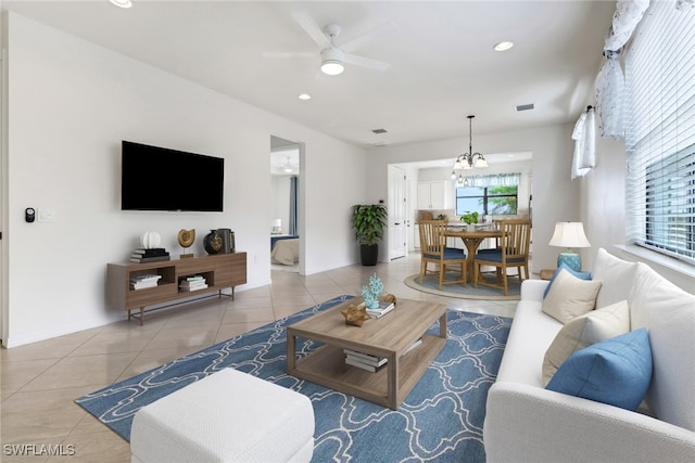 tiled living room with ceiling fan with notable chandelier