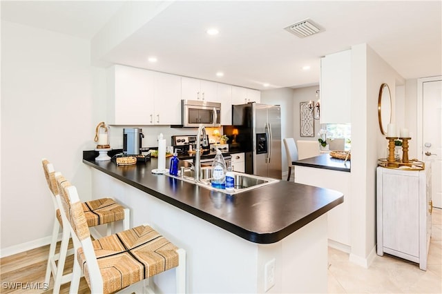 kitchen featuring appliances with stainless steel finishes, dark countertops, visible vents, and a peninsula