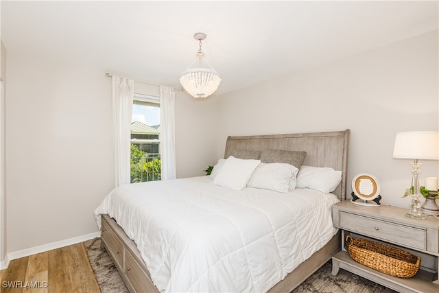 bedroom featuring baseboards, a chandelier, and wood finished floors