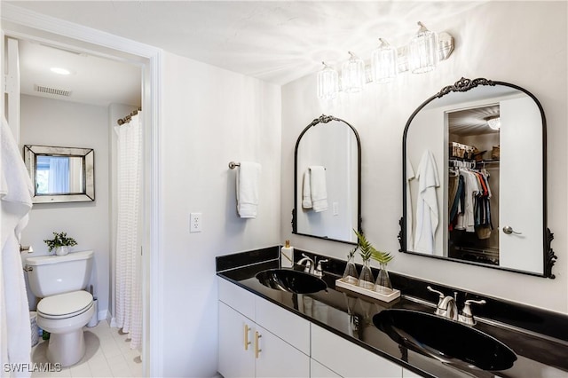 bathroom with toilet, double vanity, a sink, and visible vents