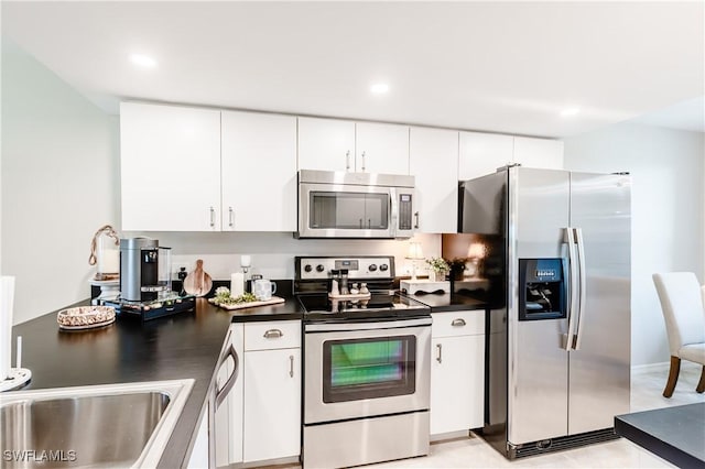 kitchen featuring appliances with stainless steel finishes, dark countertops, white cabinetry, and recessed lighting