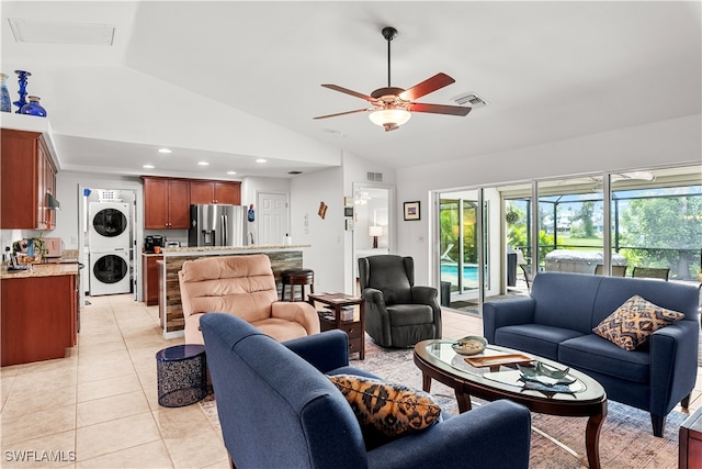 living room with lofted ceiling, ceiling fan, stacked washer / dryer, and light tile patterned floors