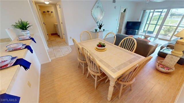 dining space with light wood-type flooring and ceiling fan