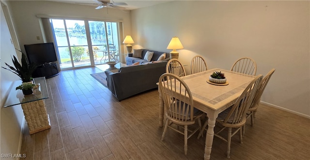 dining area with dark wood-type flooring and ceiling fan