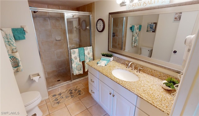 bathroom with a shower with door, vanity, toilet, and tile patterned flooring