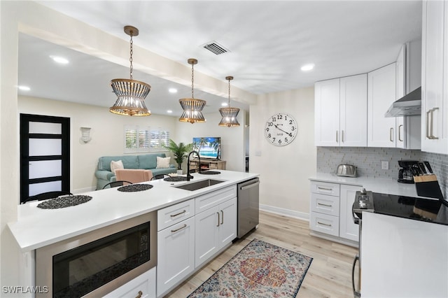 kitchen with stainless steel appliances, visible vents, decorative backsplash, a sink, and under cabinet range hood