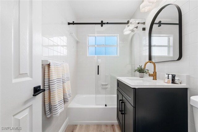 full bathroom with tile walls, bathtub / shower combination, toilet, vanity, and wood finished floors