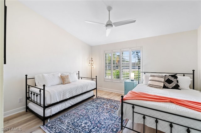 bedroom featuring a ceiling fan, lofted ceiling, baseboards, and light wood finished floors