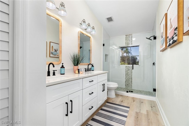 bathroom featuring a sink, a shower stall, toilet, and wood finished floors