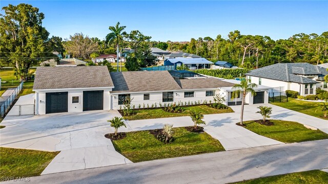 view of front of home with a garage, a residential view, concrete driveway, and fence