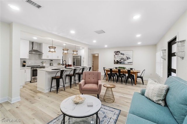 living area featuring light wood-type flooring, baseboards, visible vents, and recessed lighting