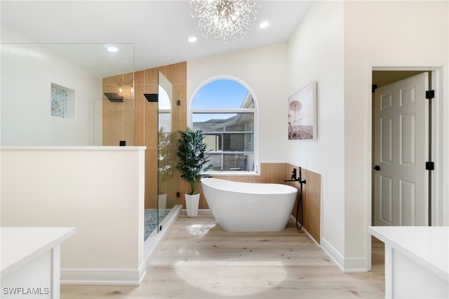 bathroom featuring a notable chandelier, recessed lighting, wood finished floors, a freestanding tub, and a walk in shower