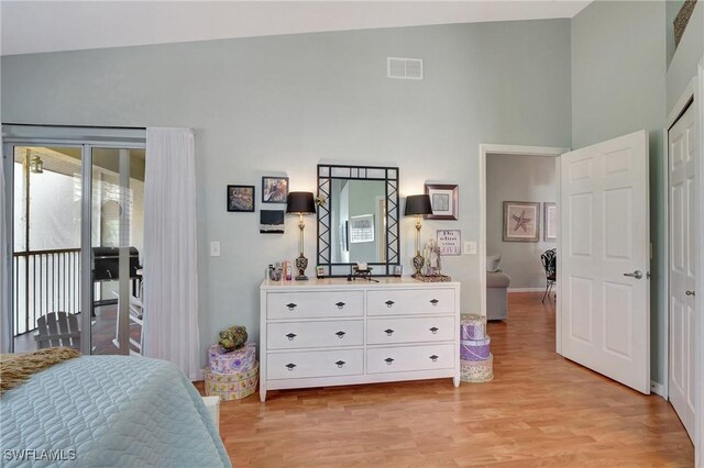 bedroom featuring high vaulted ceiling, light hardwood / wood-style floors, and access to outside