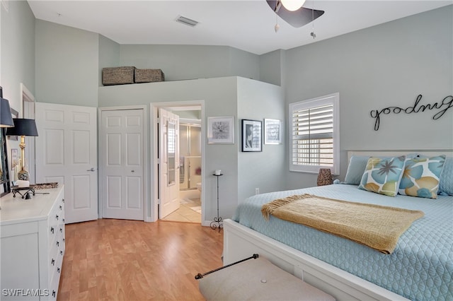 bedroom featuring a closet, ensuite bathroom, light hardwood / wood-style floors, lofted ceiling, and ceiling fan