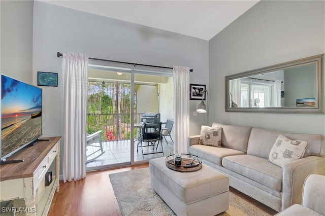 living room with plenty of natural light, high vaulted ceiling, and light hardwood / wood-style floors