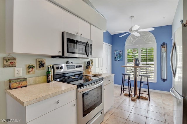 kitchen featuring light tile patterned floors, appliances with stainless steel finishes, white cabinetry, lofted ceiling, and ceiling fan