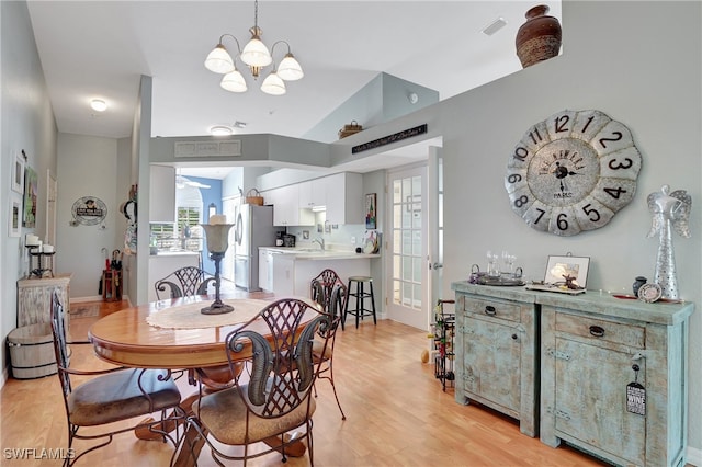 dining room with lofted ceiling, light hardwood / wood-style flooring, and a chandelier