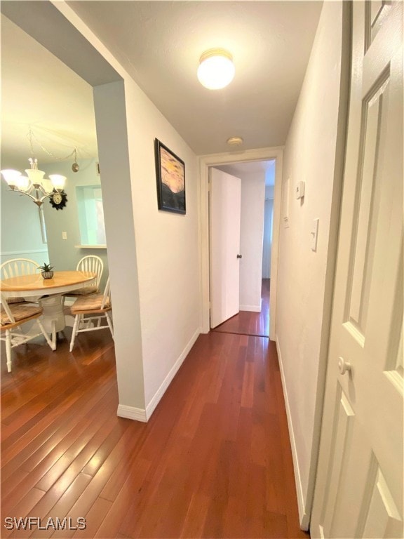 hall featuring dark hardwood / wood-style flooring and a notable chandelier