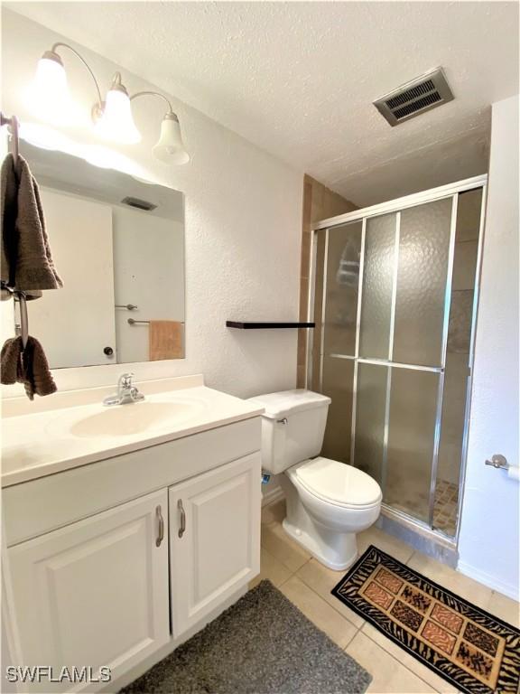 full bath with a stall shower, visible vents, toilet, tile patterned flooring, and a textured ceiling