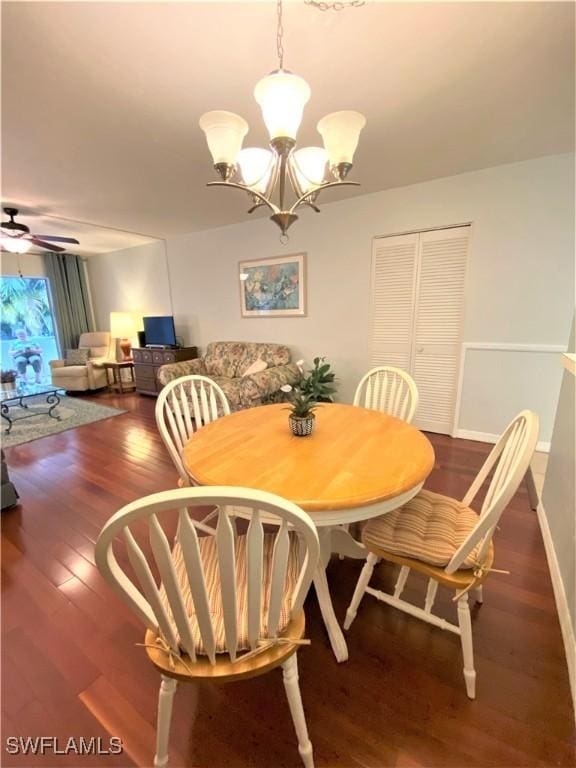 dining space featuring ceiling fan with notable chandelier, baseboards, and wood finished floors