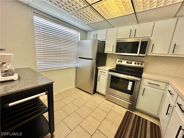 kitchen with appliances with stainless steel finishes, white cabinetry, and light tile patterned floors