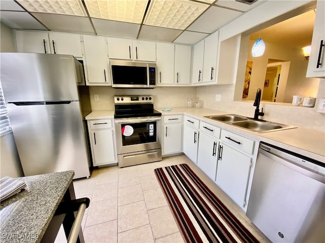 kitchen featuring light countertops, appliances with stainless steel finishes, light tile patterned flooring, a sink, and a drop ceiling