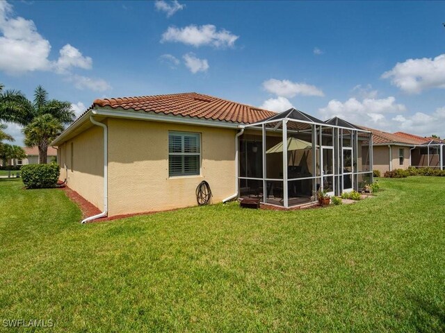 rear view of property with a lawn, a lanai, and a tile roof