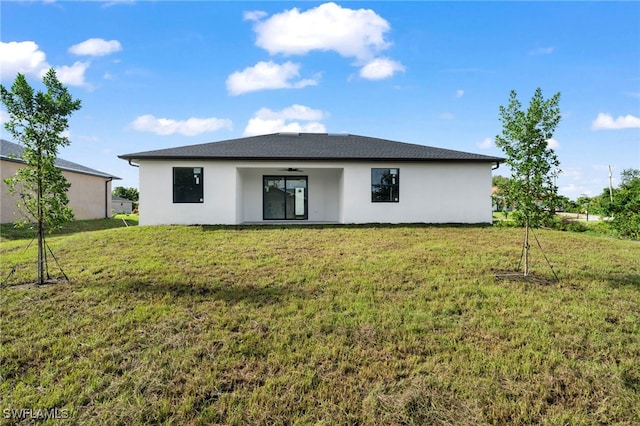 rear view of property featuring ceiling fan and a yard