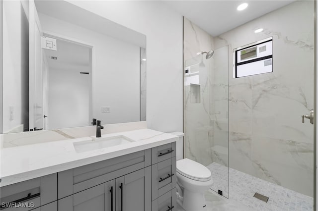 bathroom featuring vanity, toilet, and tiled shower