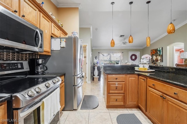 kitchen with dark stone countertops, hanging light fixtures, crown molding, stainless steel appliances, and light tile patterned flooring